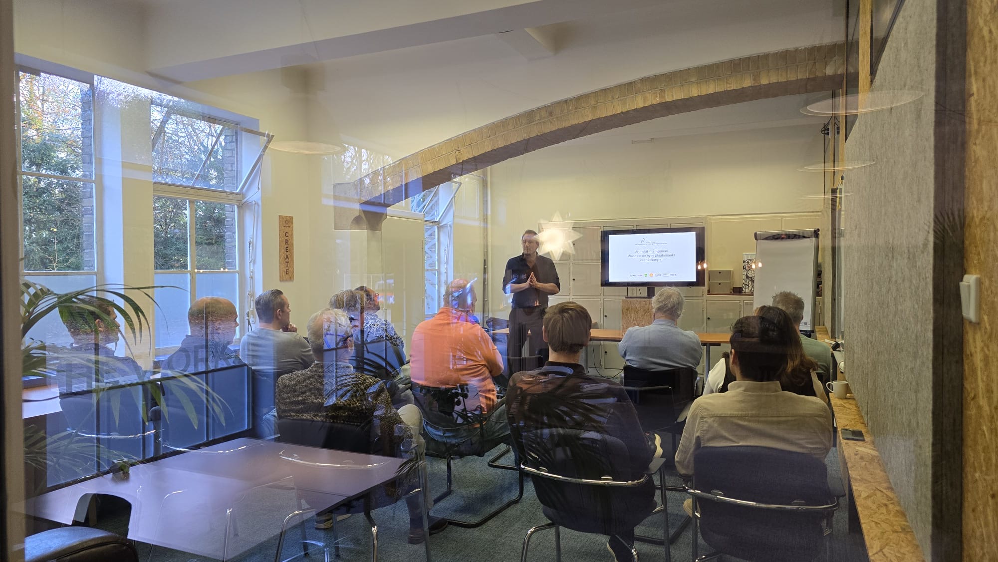 Peter geeft een AI-presentatie aan een groep volwassenen, met een groot scherm op de achtergrond.